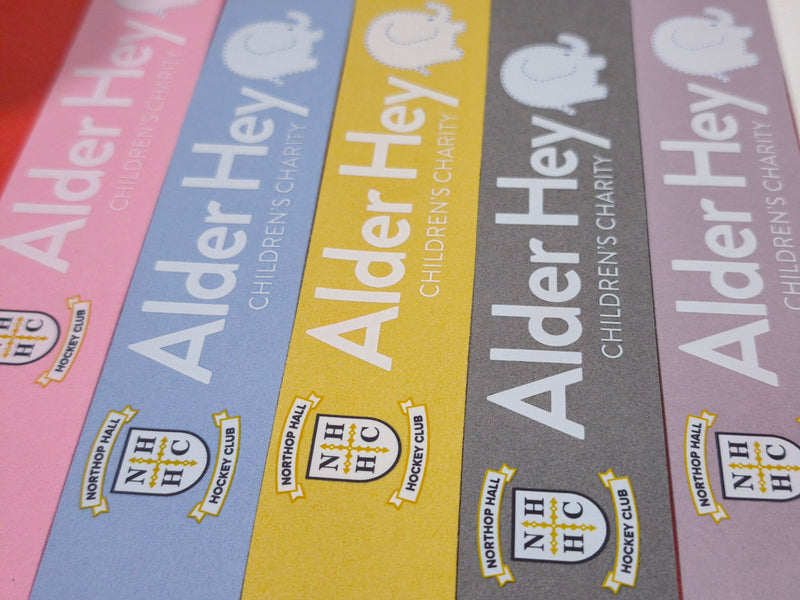 Northop Hall Hockey Club crest and the Alder Hey Children's Charity logo on a set of coloured Griptonyte grips